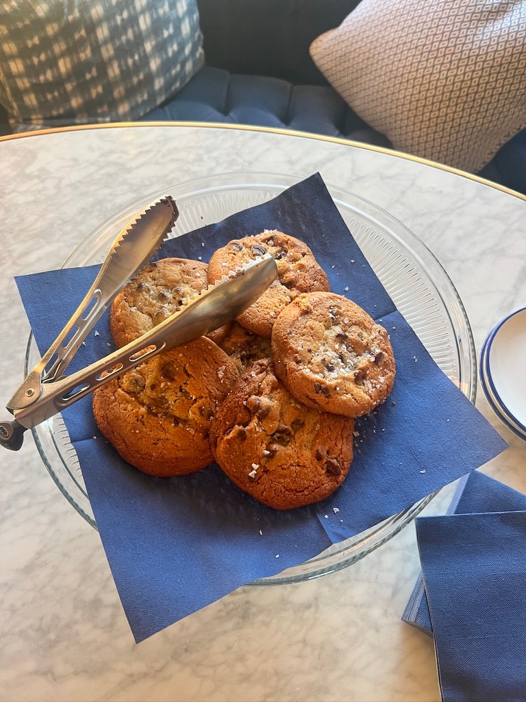 Casa Laguna Hotel and Spa welcome cookies — sea-salt chocolate chip cookies on a blue napkin in a glass bowl with gold rim, served on a marble table with blue-and-white tableware