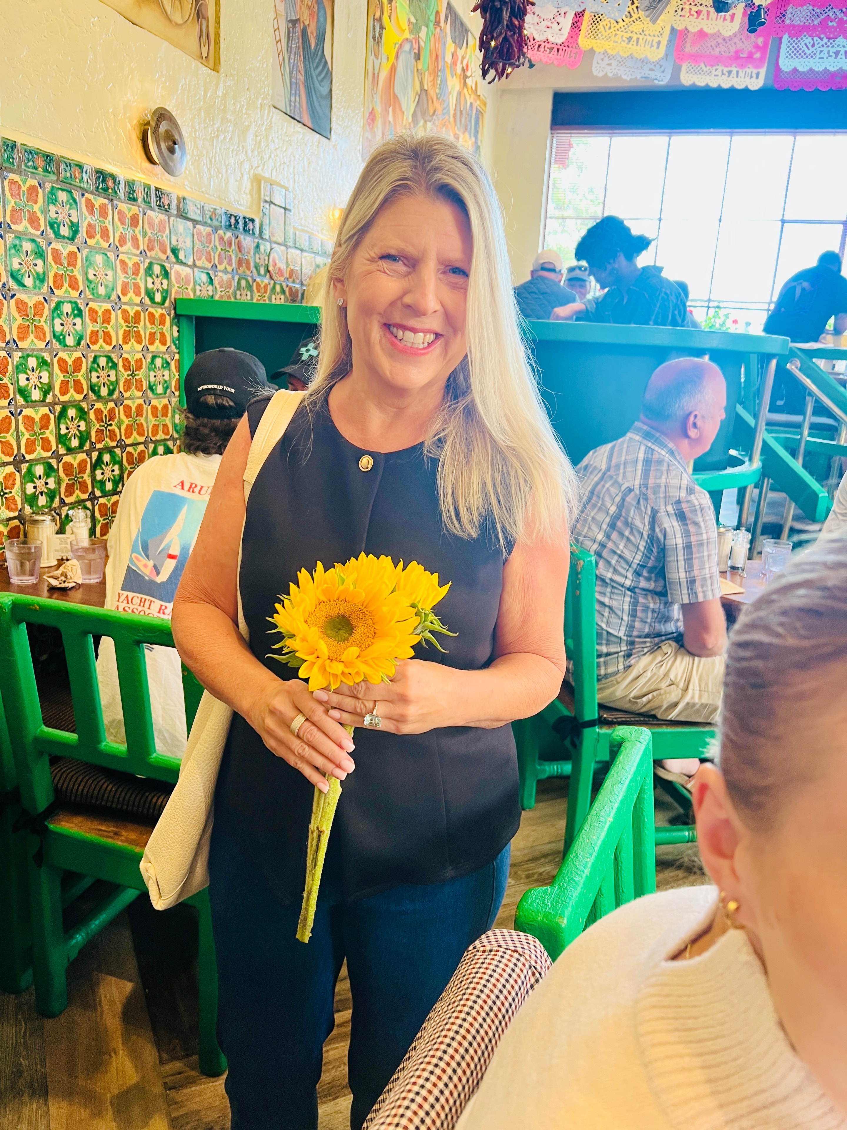 Alyssa's Ma holding sunflowers inside Cafe Pasqual's restaurant in Santa Fe, New Mexico